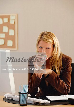 A woman looks at the camera as she drinks from a Chinese tea cup