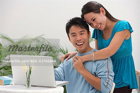 Young woman leaning on shoulder of man at the computer