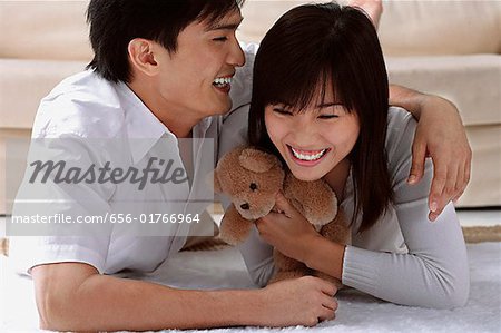 Young couple laughing while hugging and lying on the floor