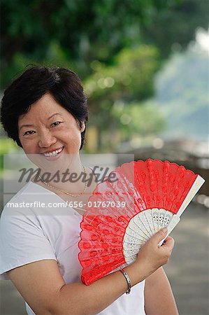 Woman with fan smiling at camera