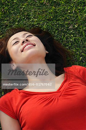 Woman smiling, lying on grass