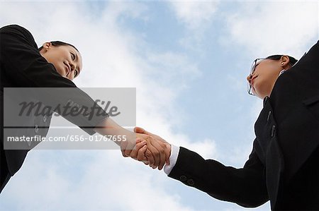 Two businesswoman shaking hands, low angle view