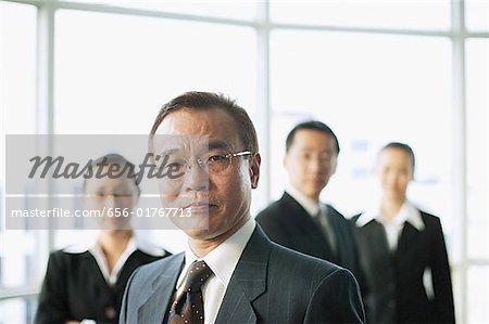 Businessman looking at camera, people in the background