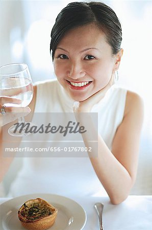 Young woman holding glass of water, smiling at camera