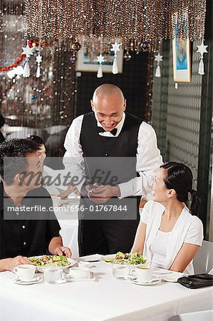 Waiter talking to couple at restaurant