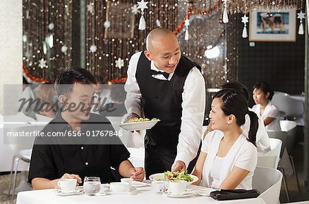 Waiter serving couple at restaurant