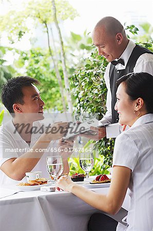 Couple in restaurant, making payment to waiter