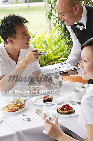 Couple in restaurant, man making payment with credit card