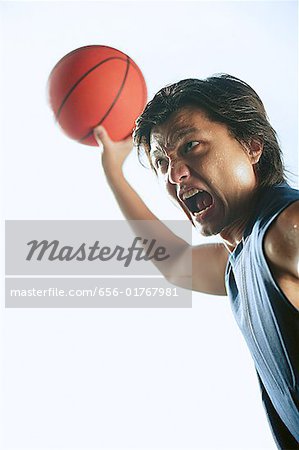 Homme tenant de basket-ball dans la bouche d'air ouvert