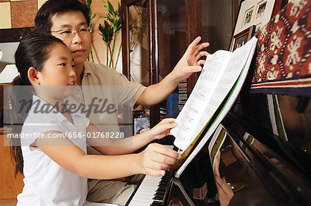 Père et fille assis au piano, à la recherche de musique en feuille