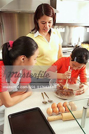 Mère et ses deux filles dans la cuisine, une cuillère tenue fille et bol