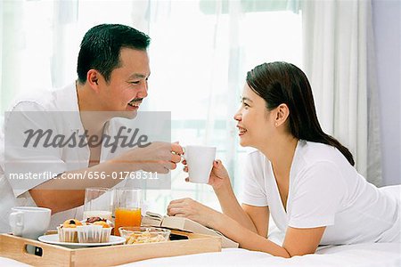 Couple dans la chambre, le petit déjeuner sur le lit