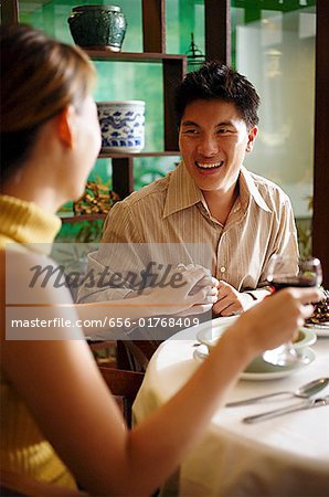 Man holding woman's hand in restaurant, ring on her finger