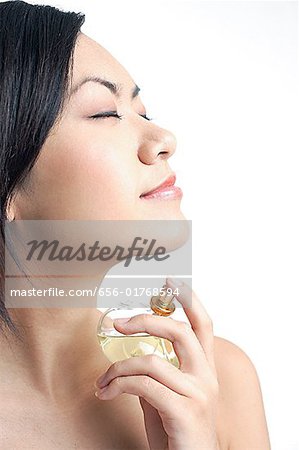 Woman applying perfume, sideview