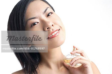 Woman holding perfume bottle, looking at camera