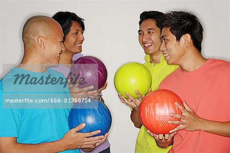 Vier Männer halten Bowlingkugeln, Lächeln