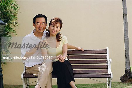 Mature Couple sitzen auf Bank, lächelnd in die Kamera