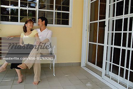 Couple assis sur un banc dans le patio, en regardant les uns les autres