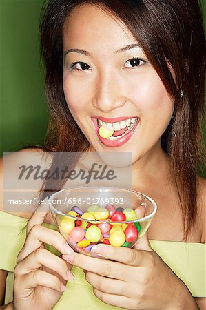 Femme mangeant des bonbons et tenant bol de bonbons