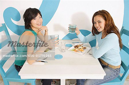 Junge Frauen mit Mittagessen im Cafe, Wassergläser Kamera auslösen