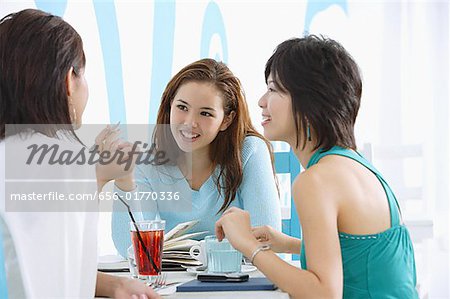 Drei junge Frauen im Cafe, im Gespräch
