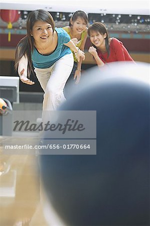 Woman bowling, friends behind her watching