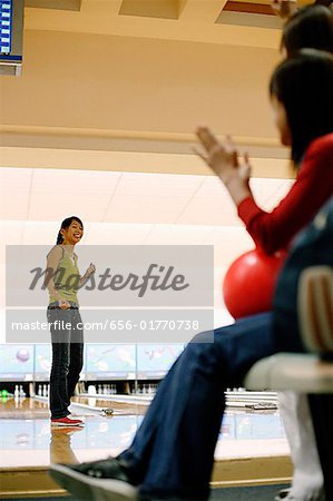 Woman at bowling alley, turning to look at friends behind her