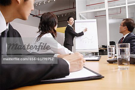 Group having a business meeting, woman writing on flipchart