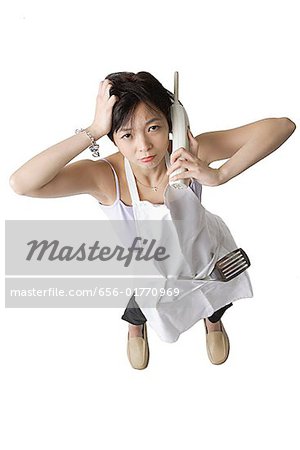 Woman in apron using cordless phone, frowning