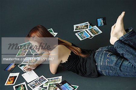 Woman lying on floor, writing on backs of postcards