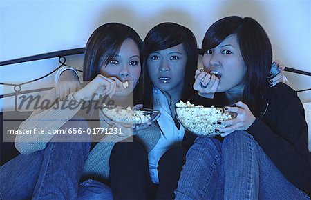 Trois filles dans la chambre, manger le pop-corn, regarder la télévision