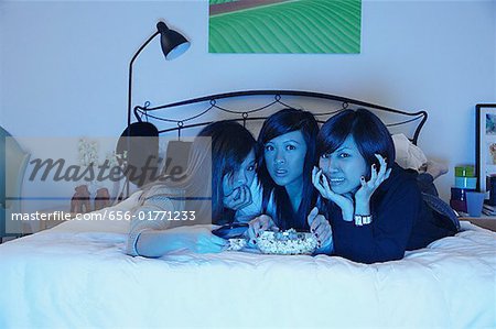 Trois filles dans la chambre, allongé sur le lit, regarder la télévision
