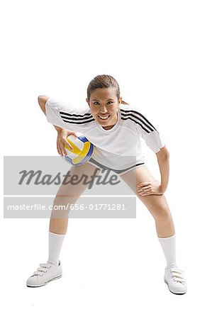 Young woman bending and holding volleyball