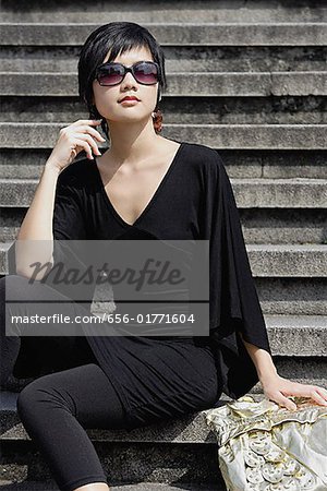 Woman dressed in black, wearing large sunglasses, sitting on steps