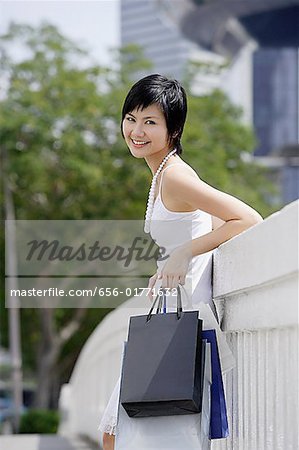 Woman with shopping bags, leaning on bridge