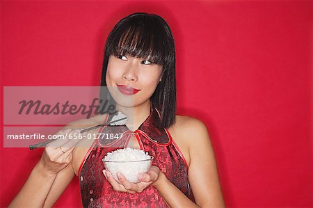 Woman against red background, holding bowl of rice