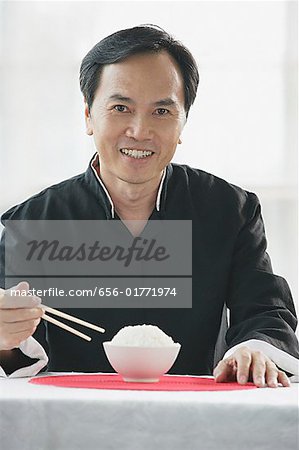 Mann mit Schüssel Reis und Stäbchen, lächelnd in die Kamera