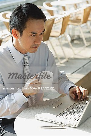 Businessman in cafe with laptop, holding mug