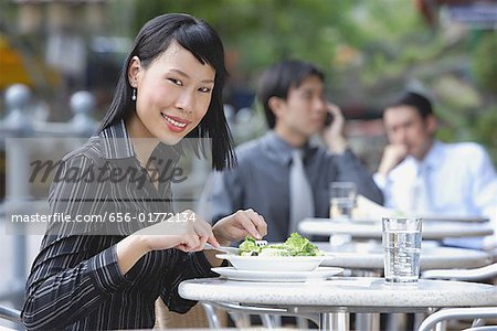 Geschäftsleute auf der Hotelterrasse, konzentrieren sich auf die Frau im Vordergrund, mit Salat