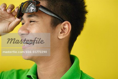 Man adjusting sunglasses, looking away