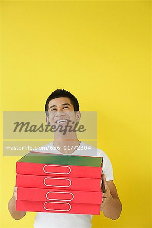 Pizza delivery person carrying a stack of pizza boxes, looking up