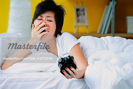 Femme au lit, radio-réveil, en regardant le bâillement