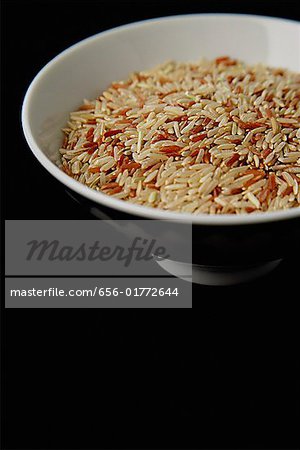 Bowl of uncooked rice against black background