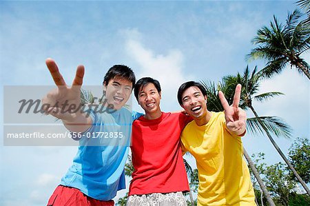 Men with arms around each other, looking at camera, making peace sign