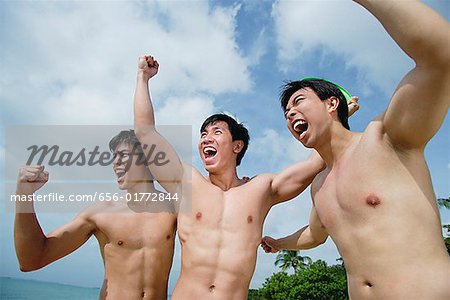 Three shirtless men raising fists