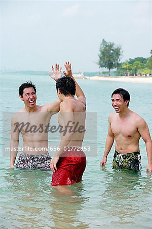 Three men standing waist deep in sea