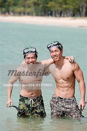 Two men standing in sea, arms around each other