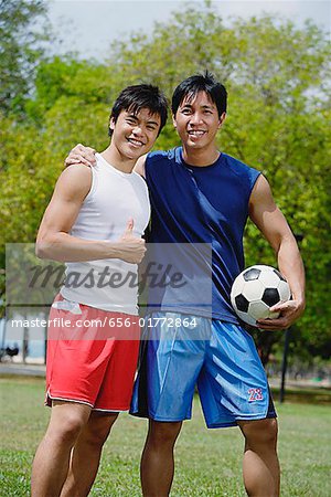 Two men looking at camera, one holding soccer ball