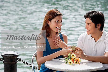 Couple assis au café en plein air, homme donnant à un cadeau femme