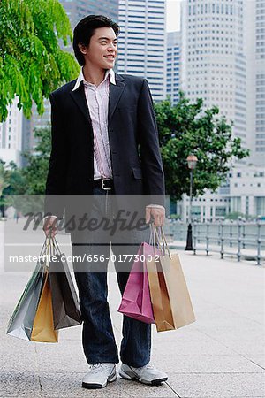 Homme debout avec sacs à provisions, à la recherche de suite